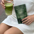 Frau hält ein Glas Matcha und die Produktverpackung Mushroom Matcha in ihrer Hand. Sitzend. 